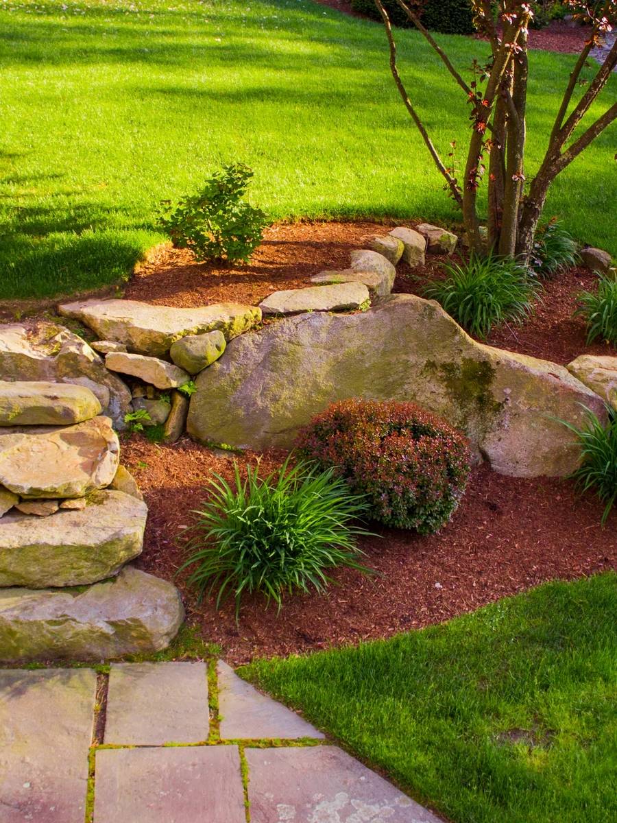 Landscape with large rocks, mulch, and plantings.